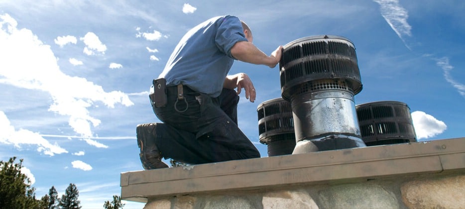 A man cleaning a gas fireplace chimney with a ladder.