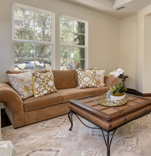 A cozy living room with a beige couch, coffee table, and a window offering a view