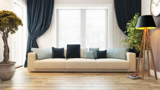 A cozy living room featuring a white couch, blue curtains, and a concealed doorway as per