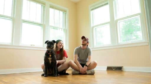 woman in gray shirt sitting on brown wooden floor