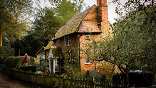 brick cottage nestled in a lush garden setting, showcasing rustic charm and tranquility. Stock Photo
