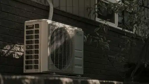 a white air conditioner sitting on top of a brick wall