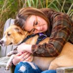 A young girl with epilepsy hugging a brown dog and wondering about how to get a free service dog for epilepsy