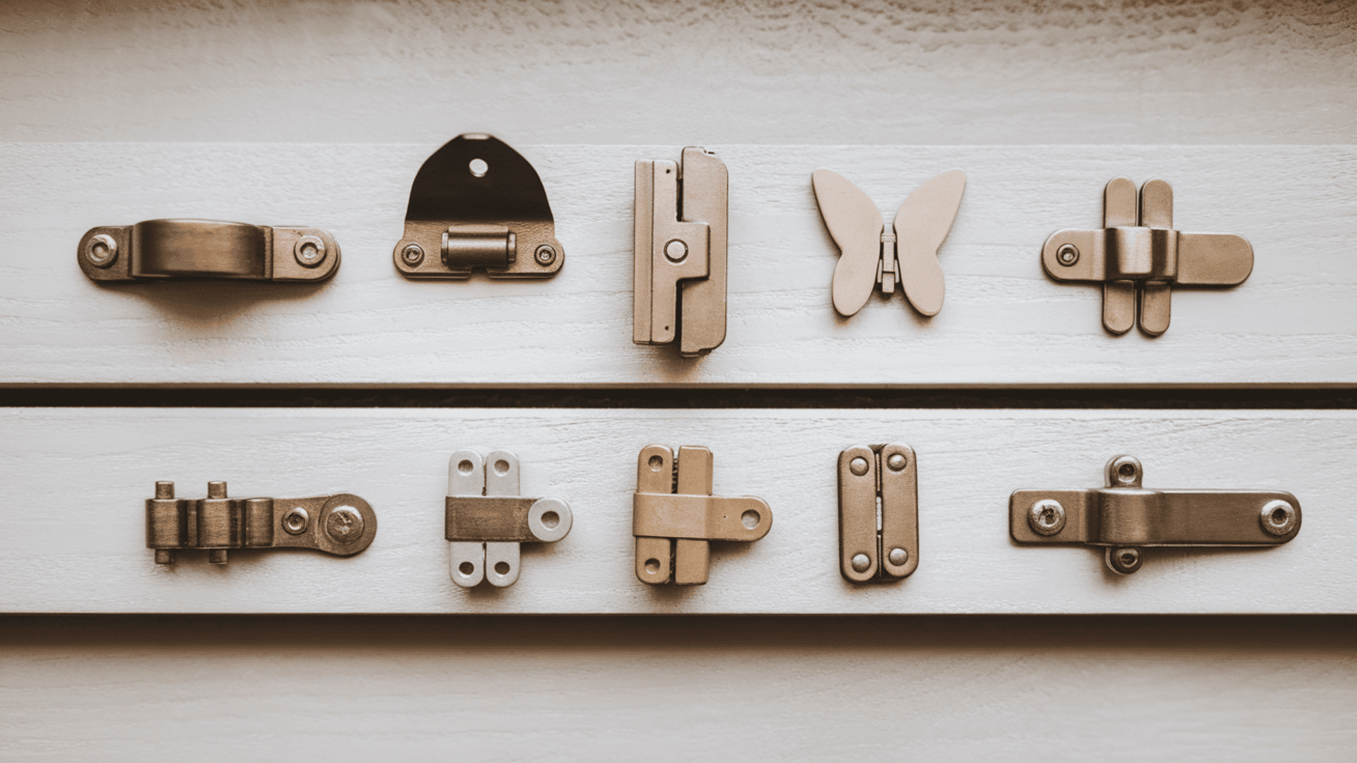 a flat lay of multiple hinge types including concealed butt butterfly strap and soft-close hinges arranged on a light grey surface
