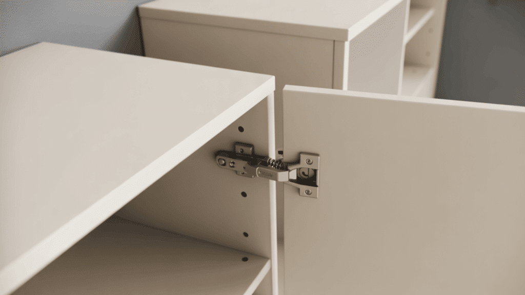 demountable cabinet hinge on a white modular flat pack unit showing the quick release spring mechanism and mounting plate