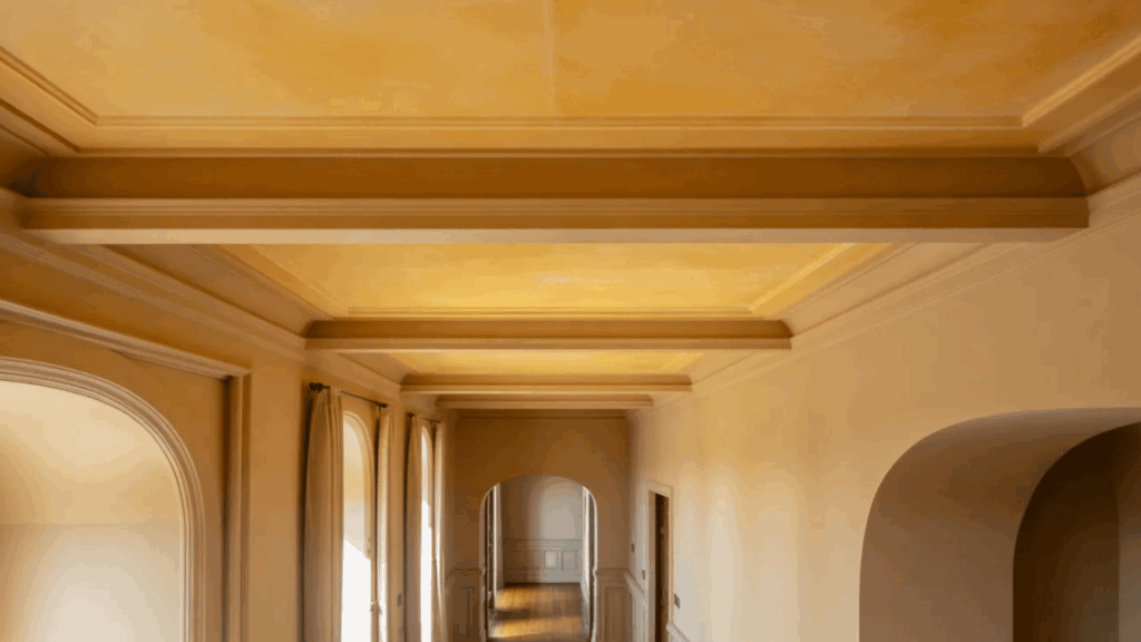 elegant hallway with a yellow toned ceiling, detailed molding, and arched doorways
