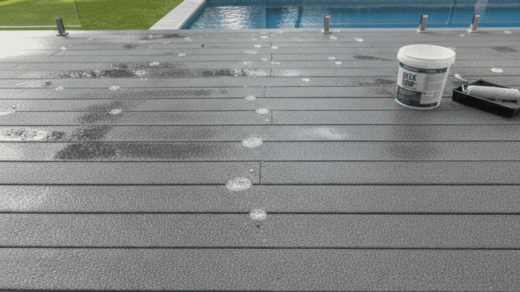 gray textured anti-slip deck surface near swimming pool with paint bucket and roller tray visible.