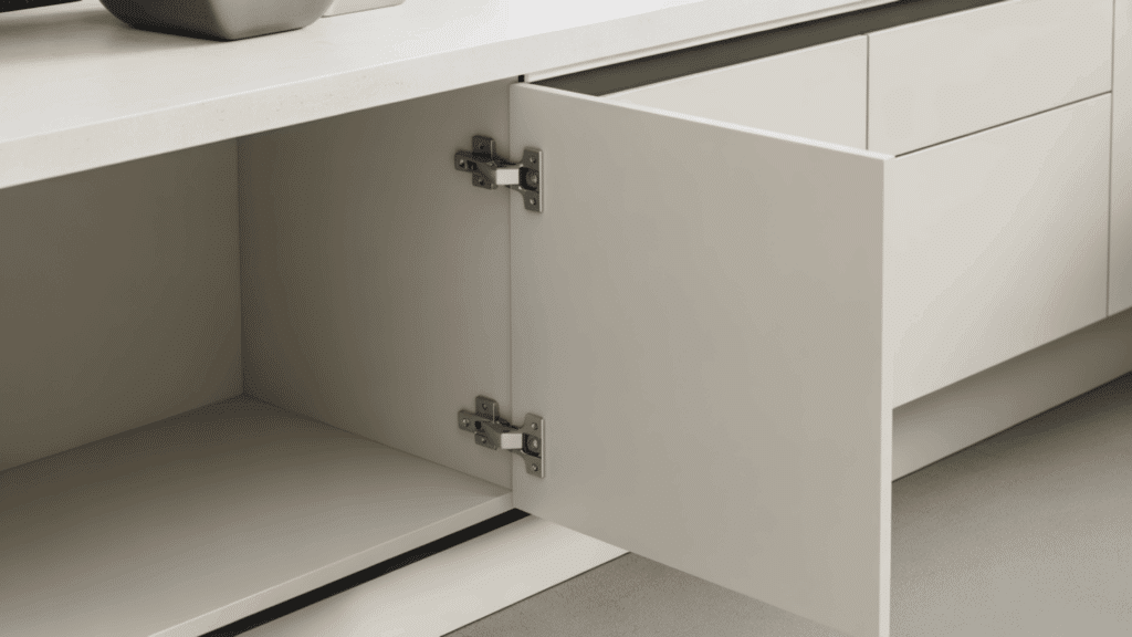 two silver pivot hinges on an open cream frameless cabinet door showing top and bottom mounting points with no side hardware