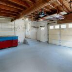 Spacious garage with blue and red cabinets.